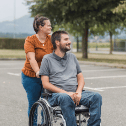 Disabled man in wheelchair outside with support worker