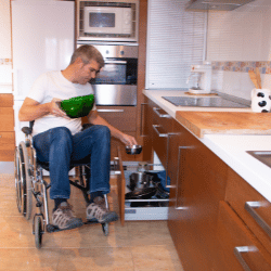 Disabled man in wheelchair putting dishes away in kitchen