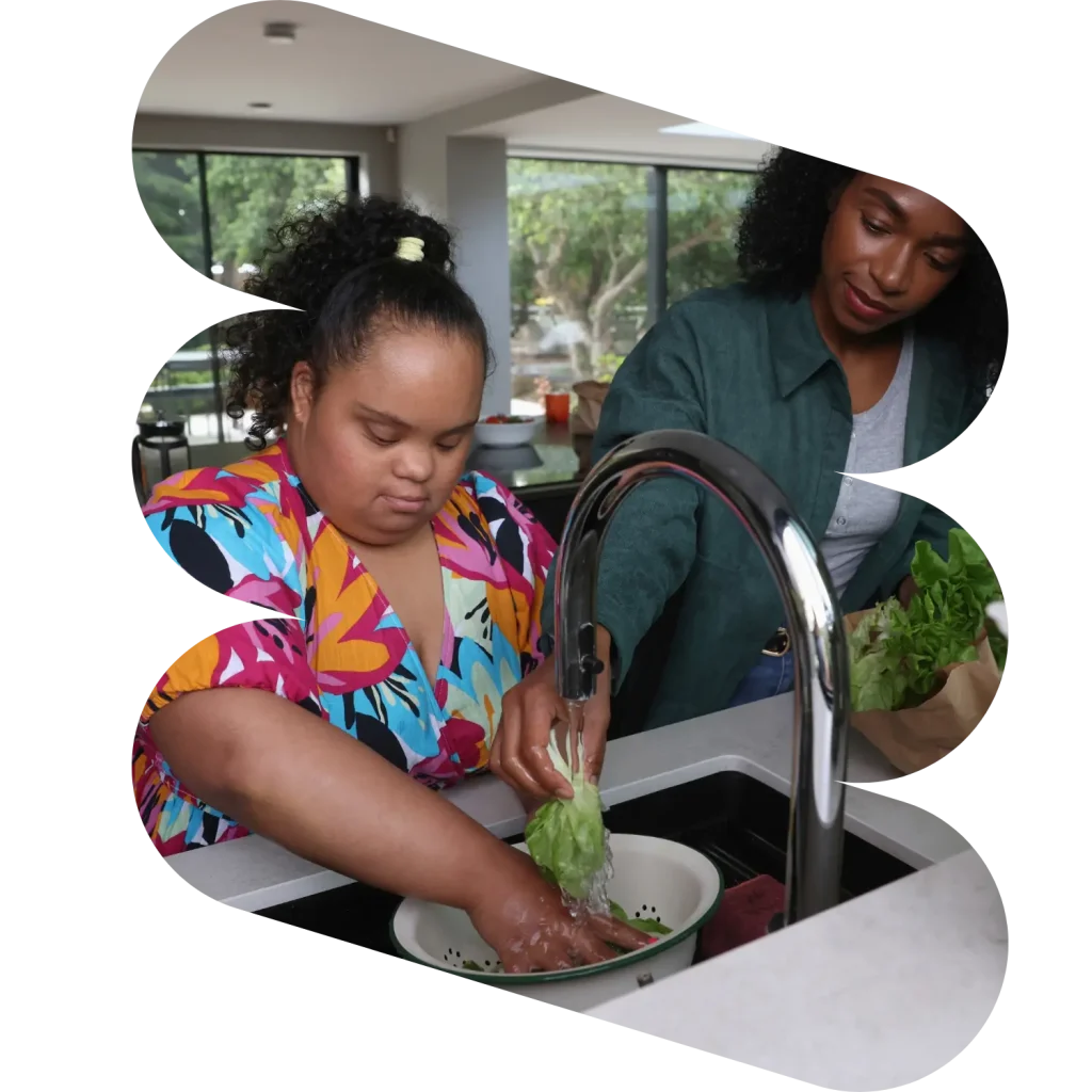 Disabled woman washing vegetables in kitchen with support worker