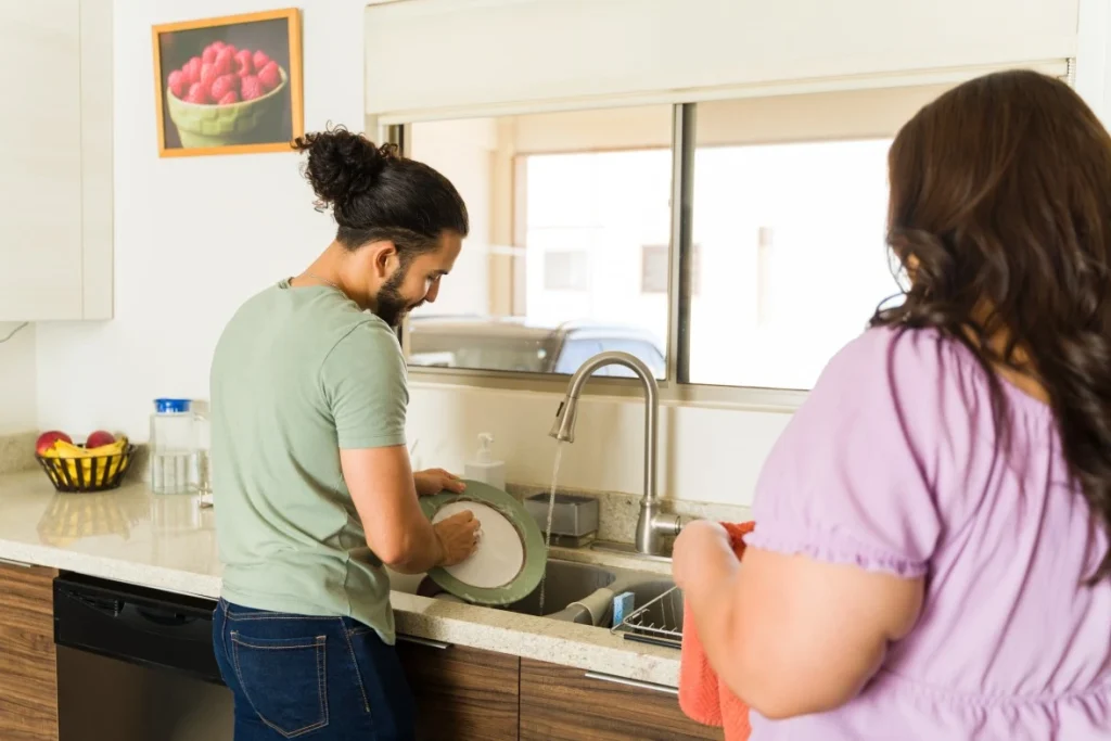 Two support workers washing dishes in kitchen